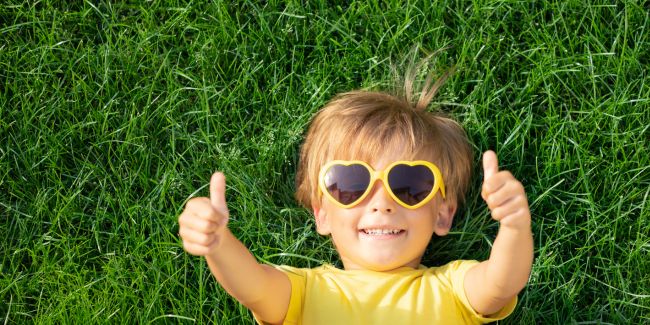 Child on grass with thumbs up