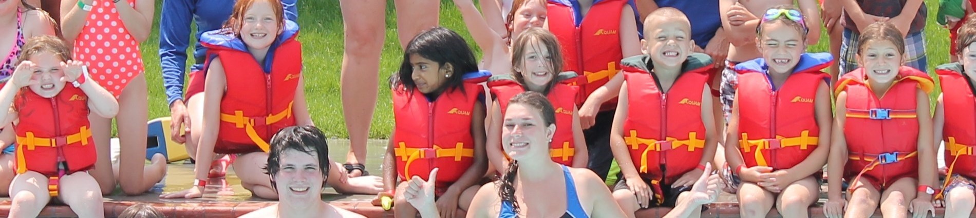 kids in lifejackets in pool